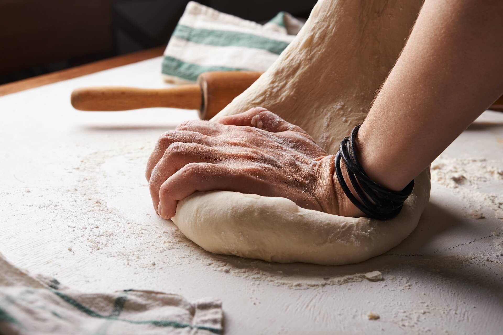 person making pizza dough beside brown wooden rolling pin