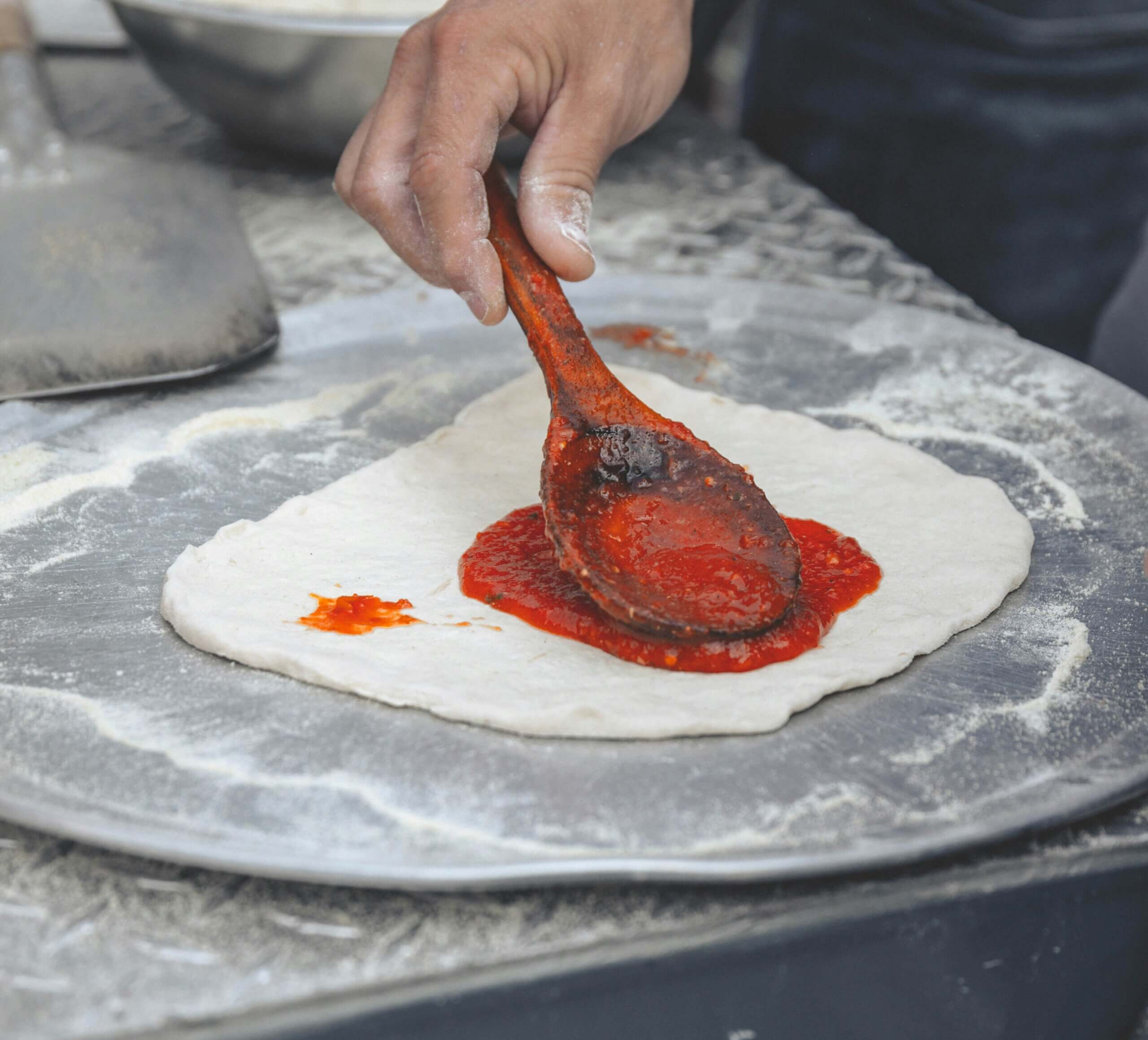A person prepping a Pizza